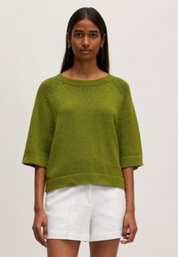 Groen gebreid sweater met een boxy pasvorm, korte mouwen, geribbelde halslijn en zoom; gecombineerd met witte shorts. Gestructureerde stof met een subtiele glans.
