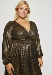 Fekete ruha arany csillogással, mély V-kivágással, hosszú puff ujjakkal és amyolított derékrésszel. Puha anyag, fényvisszaverő textúrával.