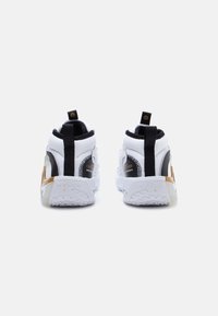 Białe i czarne sneakersy typu high-top, z górną częścią z teksturowanej tkaniny, złotymi akcentami i wzorzystą gumową podeszwą. Czarnie taśmy do wsuwania.