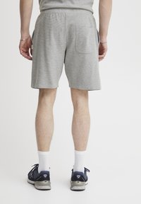 Grå bomuldsshorts med elastisk talje, der har to baglommer. Båret med navy sneakers og hvide ankelsokker.