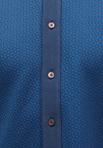 Tissu bleu texturé avec une patte de boutonnage verticale bleu marine comportant trois boutons bruns à quatre trous.