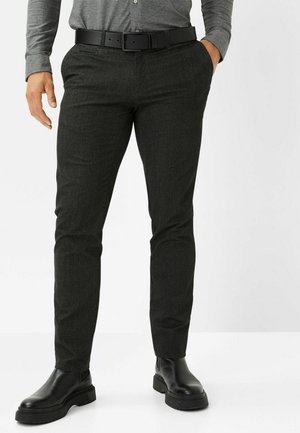 Dunkelgraue maßgeschneiderte Hose aus einem strukturierten Stoff, mit einem schwarzen Gürtel und geradem Schnitt, kombiniert mit schwarzen Stiefeletten.