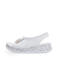 Weiße Leder-Sandalen mit offenen Zehen, die über ein dekoratives Detail und eine gesprenkelte weiße und schwarze Sohle verfügen. Slingback-Design für zusätzlichen Halt.