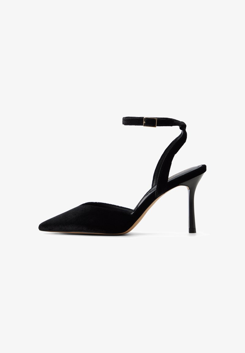 Schwarzer Samt-High-Heel-Schuh mit spitzem Zeh, Knöchelriemen und schlankem Stilettosh heel. Hat eine glatte Textur und goldene Hardware-Akzente.
