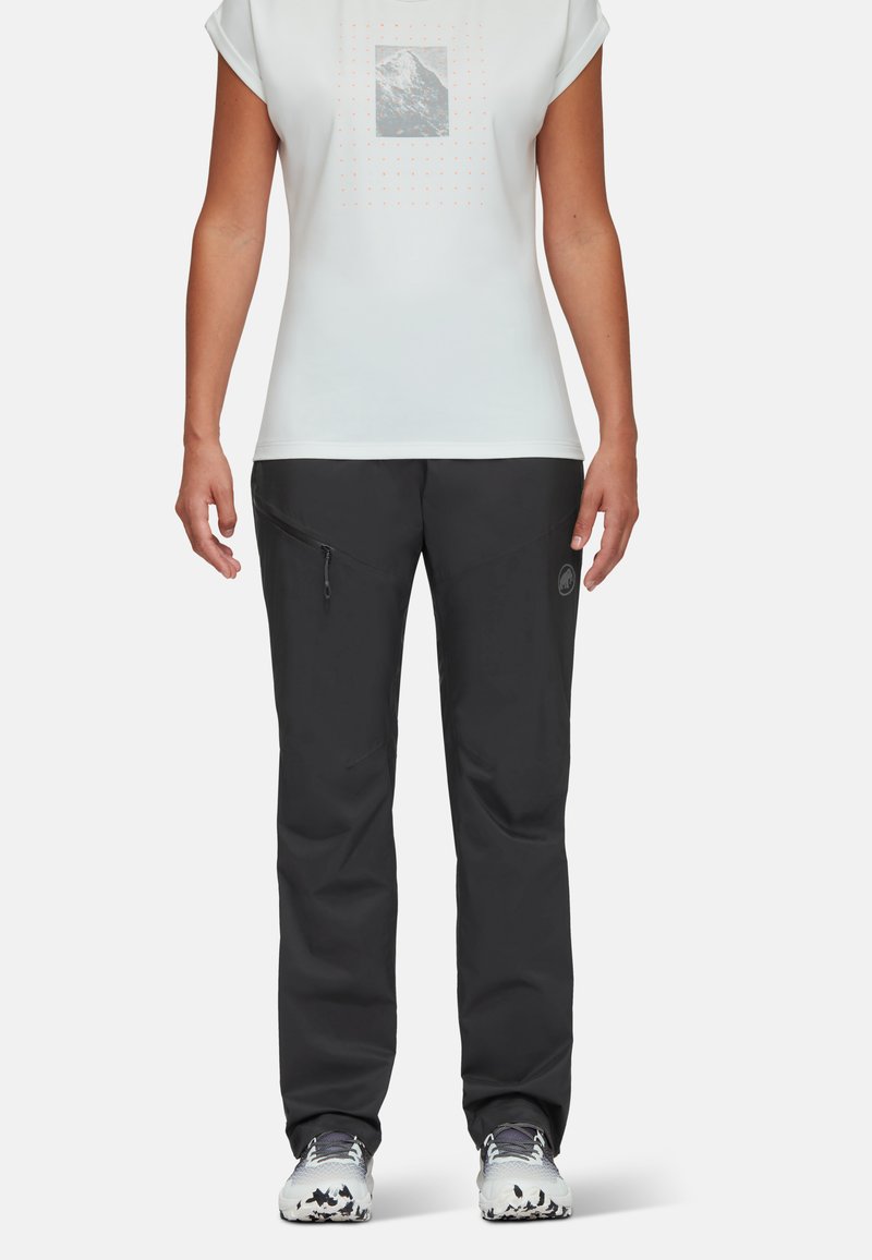 Svarta utomhusbyxor med en ficka med dragkedja, i kombination med en ljusgrå t-shirt med en bergsgrafik och prickar. Utformade för aktiv användning.