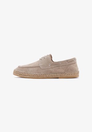 Bottine espadrille en daim beige avec un bout rond, deux œillets pour les lacets et une semelle intermédiaire en jute tressé. Semelle extérieure en caoutchouc plate. Design simple.