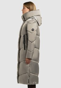 Langer grauer Steppmantel mit hohem Kragen, großer Kapuze und diamantgestepptem Muster. Verfügt über Reißverschlusstaschen und ein Logodetail am Arm.