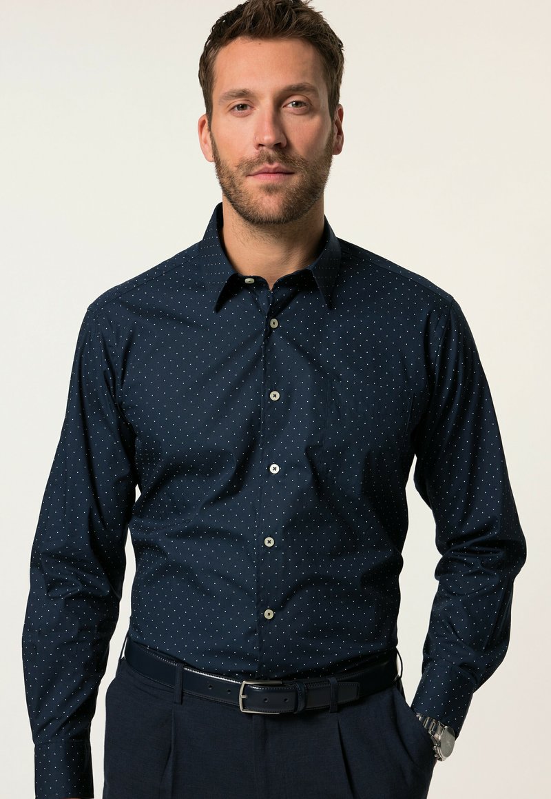 Camicia blu navy con bottoni, a pois bianchi, maniche lunghe e colletto standard. Presenta bottoni a contrasto e una tasca sul petto.
