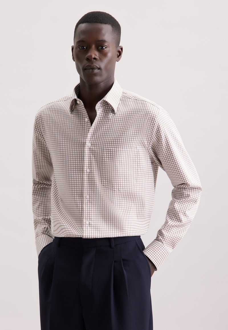 Camicia a maniche lunghe a quadri beige e marrone con colletto a bottone. Presenta una tasca e un design attillato, abbinata a pantaloni scuri.