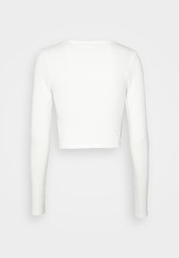 Långärmad vit croptopp i ribbat material, med rund halsringning och figurnära silhuett, av slätt, odekorerat tyg.