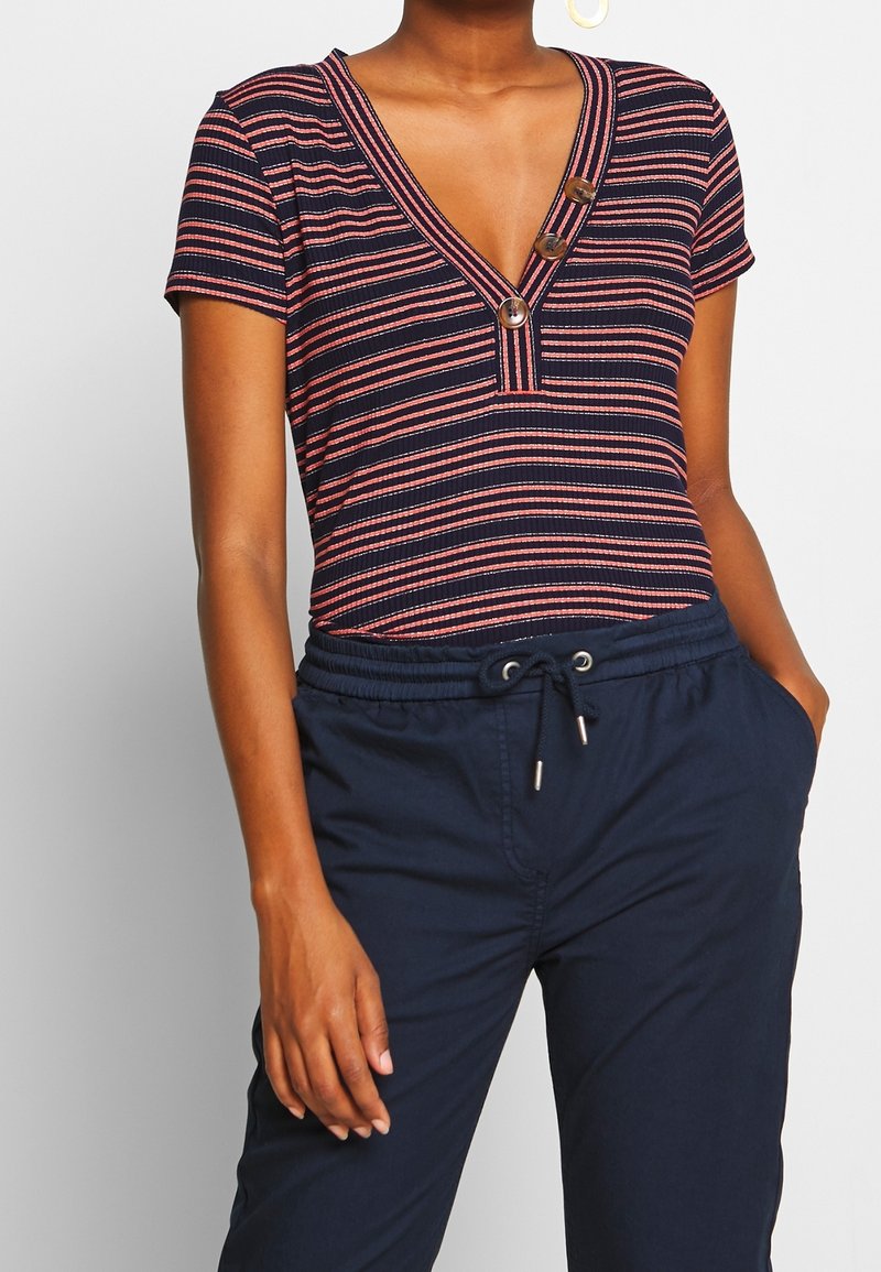 Pasiasty bodysuit z krótkim rękawem w kolorze granatowym i koralowym, z głębokim dekoltem w kształcie litery V oraz trzema guzikami z przodu, z prążkowaną fakturą i dopasowanym krojem.