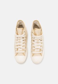 Pair of beige high-top canvas sneakers with white rubber toes and laces, viewed from above on a white background.