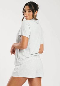 Lichtgrijze geribbelde loungewearset met een T-shirt met korte mouwen en bijpassende shorts. Zachte stof met een relaxte pasvorm en een zakdetails op het shirt.