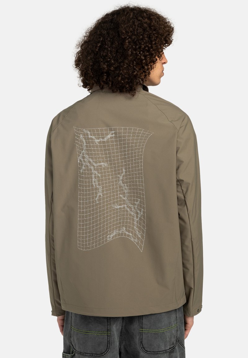 Light brown jacket with a grid-patterned white graphic on the back. Features a smooth texture and long sleeves, designed for casual wear.