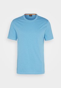 T-shirt bleu clair à manches courtes avec col ras du cou, présentant une texture minimale et un petit logo sur la poitrine, affiché sur un fond blanc.