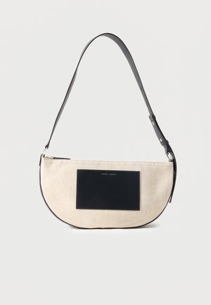 Sac à épaule beige en forme de demi-lune avec une sangle noire réglable et un patch rectangulaire noir à l'avant.