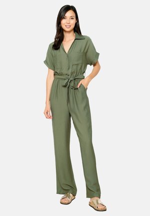 Combinaison olive green avec manches courtes, boutons sur le devant, deux poches poitrine, taille ceinturée et pantalon ample. Tissu lisse et léger.