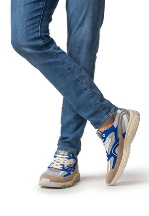 Lichte sportsneakers met een grijze mesh bovenkant, blauwe accenten, beige suède details en gestructureerde zolen. Draagt bij blauwe jeans.