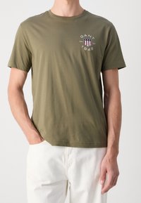 Kortärmad t-shirt i olivgrönt gjort av mjuk bomull. Har en logga med röda, vita och blå detaljer på vänster bröst. Normal passform.