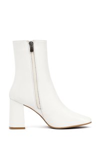 Bottines blanches en cuir lisse, avec un talon large, une pointe pointue et une fermeture éclair sur le côté.