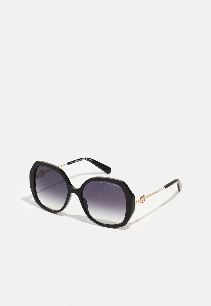Schwarze übergroße Sonnenbrille mit einem markanten achteckigen Rahmen, Farbverlaufslinsen und goldfarbenen Akzenten an den Bügeln.