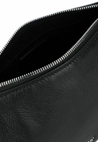 Zwarte leren pouch met een gestructureerd oppervlak en een ritssluiting in zilvertint. Het interieur is glad en ongepatteerd. Heeft subtiele branding aan de zijkant.