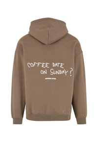Brun bomullshoodie med en stor hette, med hvit tekst på baksiden som leser «KAFFEDATE PÅ SØNDAG?» og «EN ANNEN BOMULL» under.