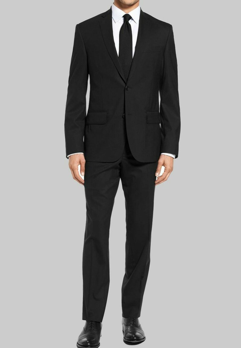 Costume noir avec deux poches avant, veste à un bouton et pantalon assorti. Porté sur une chemise blanche et une cravate noire, présentant une texture lisse.