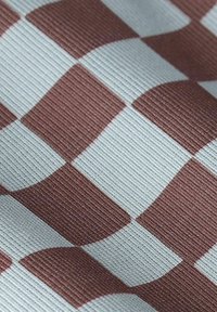 Golfabriek met een geweven textuur met een herhalend patroon van bruine en lichtgrijze schaakbordvierkanten.