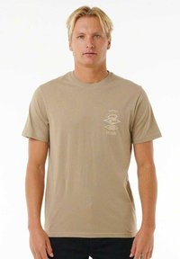 T-shirt beige a maniche corte con collo rotondo. Presenta un piccolo logo bianco sulla parte superiore sinistra del petto. Tessuto di cotone liscio, vestibilità comoda.