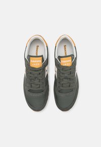 Grønne semskede og net sneakers med oransje detaljer, hvit mellomsåle og svart gummisåle. Har tradisjonelle snøringer og merkevare på tungen.