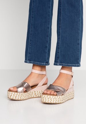 Sandały na koturnie z metalicznym srebrnym paskiem krzyżowym, jasnoróżowym obcasem i plecioną podeszwą, z regulowanym paskiem na kostce.