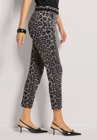 Leopardenmuster-Hosen mit grauem Grund und schwarzen Akzenten; taillierter Schnitt und knöchellang. Kombiniert mit schwarzen Slingback-Absätzen.