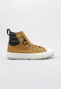 Zapatillas altas de deporte con material de ante color marrón claro y tobillo en cuero negro, cordones beige, ojales de metal y suela de goma blanca.