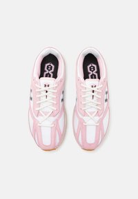 Scarpe sportive rosa e bianche realizzate in materiale mesh e scamosciato, con un logo laterale decorato e lacci bianchi su una suola in gomma.