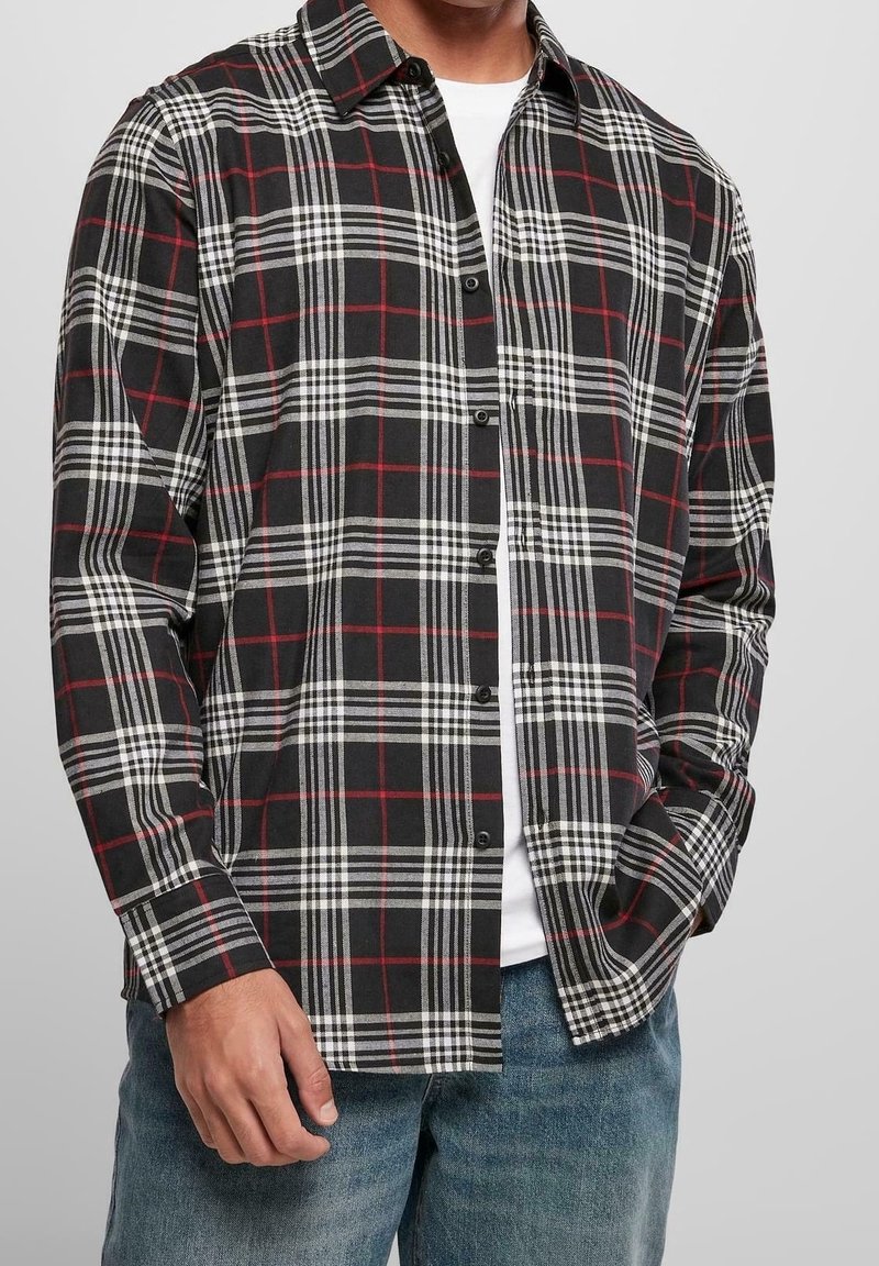 Camicia a quadri neri, bianchi e rossi con bottoni, realizzata in tessuto morbido, caratterizzata da un colletto, maniche lunghe e bottoni neri.