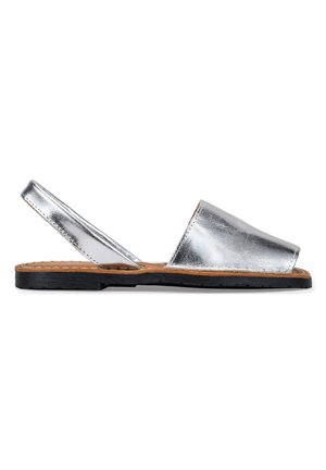 Sandalias de piel plateada metálica con tira al talón, suela plana de goma negra y diseño de punta abierta, con plantilla interior de color marrón cosida.