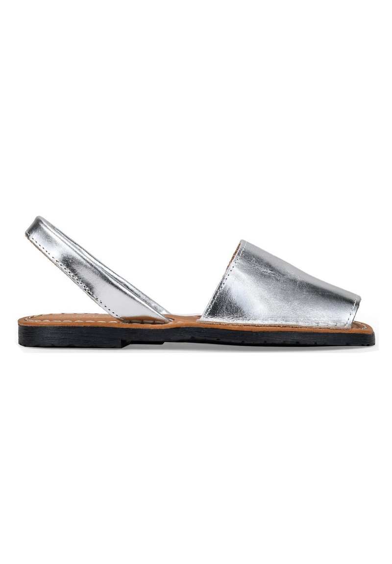 Sandalias de piel plateada metálica con tira al talón, suela plana de goma negra y diseño de punta abierta, con plantilla interior de color marrón cosida.
