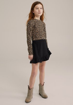 Långärmad topp med leopardmönster matchad med en svart volangkjol. Outfiten kompletteras av beiga ankelskor med texturerad yta.