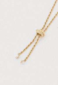 Naszyjnik w kolorze złotym z wykręcanymi łańcuchami i ozdobnym elementem centralnym, przyozdobionym cyrkoniami oraz dwoma perłowymi akcentami na końcach.