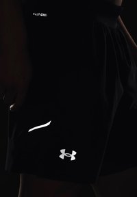 Schwarze sportive Shorts mit einem reflektierenden Logo und Akzenten, hergestellt aus leichtem, atmungsaktivem Material mit lockerer Passform.