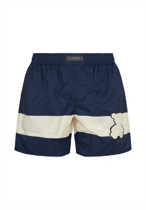 Navy blue swim shorts with a wide white horizontal stripe and a teddy bear outline logo on the left leg, elastic waistband with "ICEBERG" label.