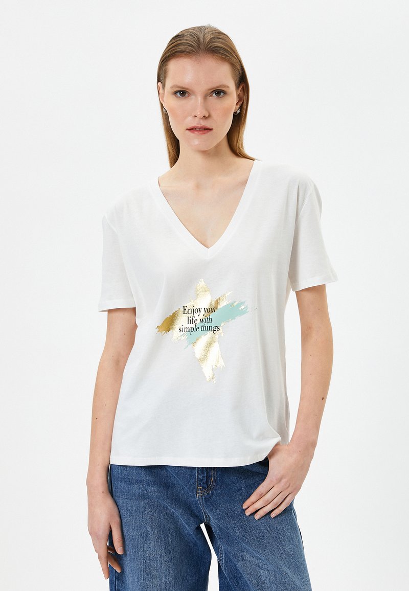 Camiseta blanca de cuello en V hecha de algodón, que presenta un diseño impreso en dorado y azul con el texto "Disfruta tu vida con cosas sencillas."