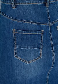 Jeans krilo v temno modri barvi z enim zadnjim žepom. Ima vidne šive v kontrastni oranžni barvi in prilegajočo se obliko. Gladka tekstura.