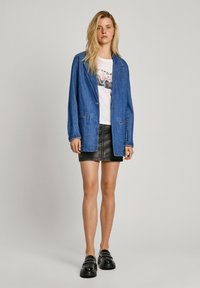 Jeansjacka i ljusblått, lager på en vit t-shirt med grafiskt tryck. Kombinerad med en svart läderkjol och kraftiga svarta skor.