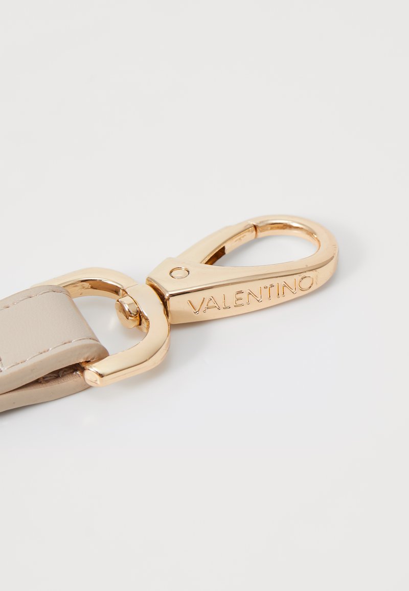 Correa de cuero beige con un cierre giratorio de metal en tono dorado, grabado con "VALENTINO", que presenta un acabado suave y bordes redondeados.