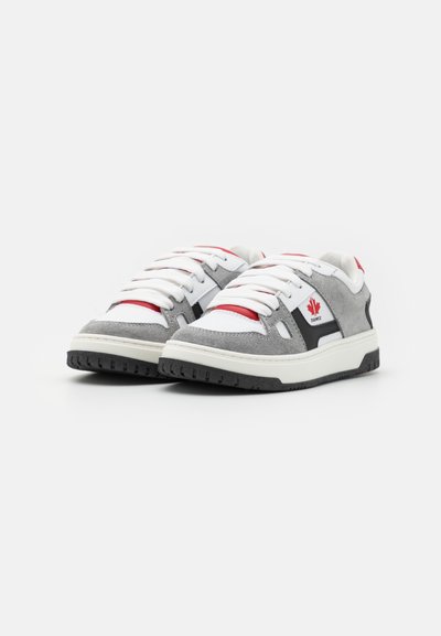 Sneaker grigi e bianchi con accenti rossi, materiali in camoscio e pelle, forma della punta rotonda, spesse stringhe bianche e suola in gomma nera testurizzata.