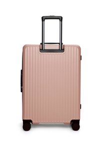 Růžový pevný kufr s vertikálními žebry, černou teleskopickou rukojetí a dvojitými kolečky; boční rukojeť pro snadné zvedání.