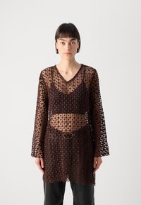 Brown lace top featuring a V-neck and long bell sleeves, with a floral pattern and a fitted silhouette, layered over a dark undergarment.