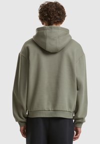 Green hooded sweatshirt made of soft fabric, featuring a relaxed fit, drop shoulders, ribbed cuffs, and a spacious hood.